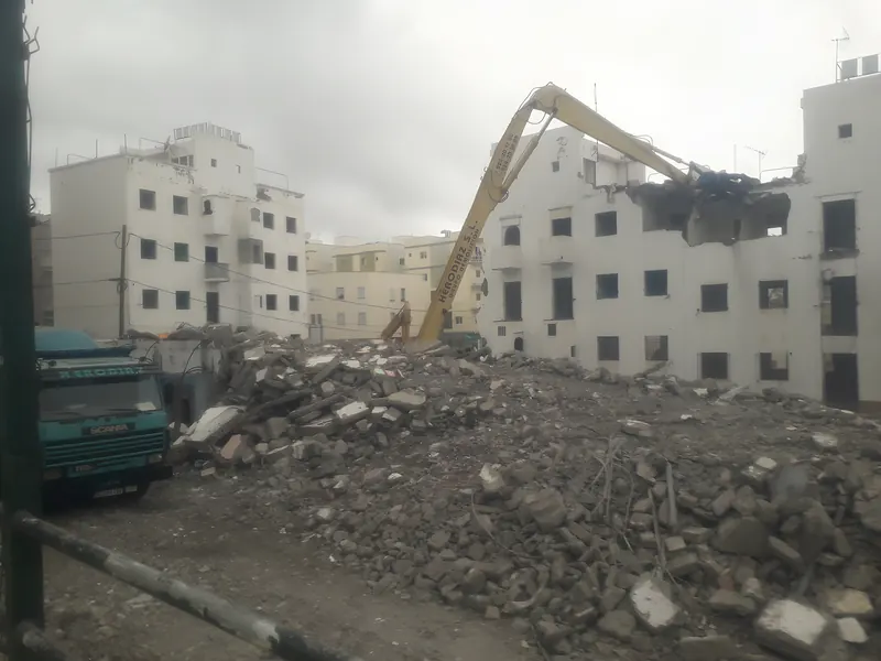 Derribo de un edificio de varias plantas con montaña de escombro en primer plano