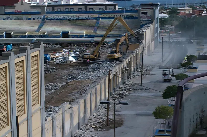 Retroexcavadoras derribando el graderío de un estadio con el puerto de Las Palmas al fondo