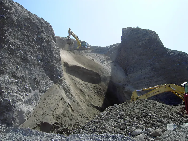 Excavadoras trabajando en un desmonte entre grandes taludes de tierra