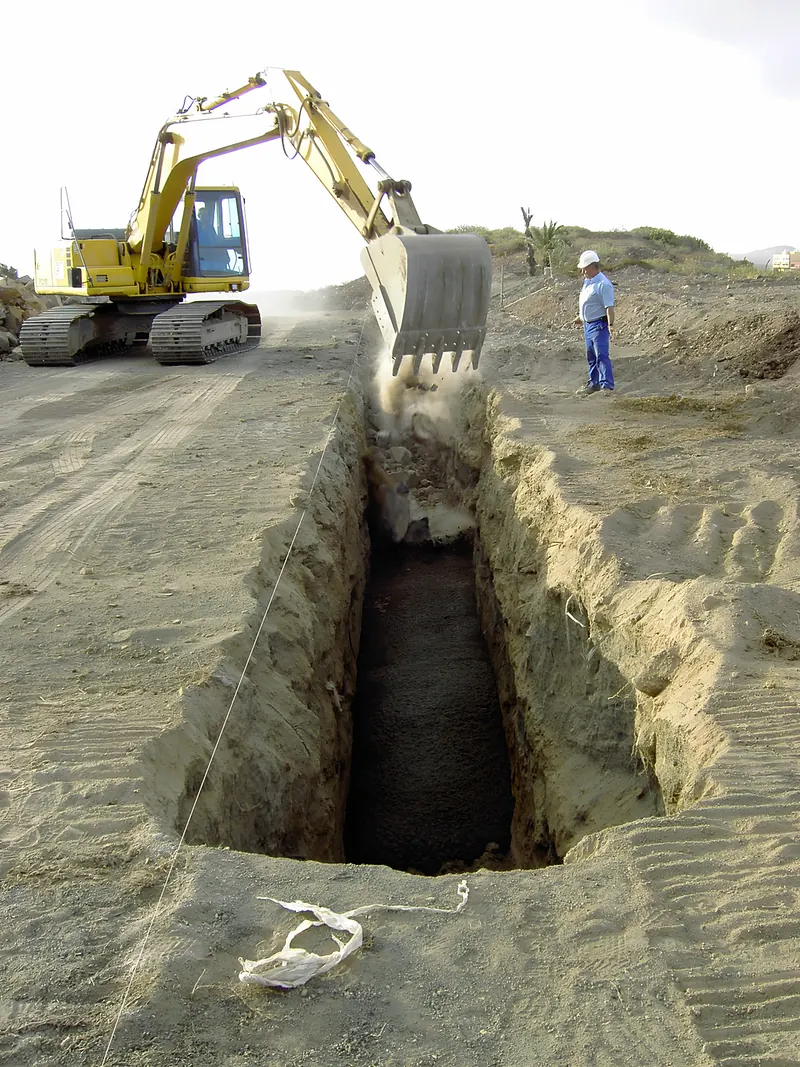 Excavadora abriendo una zanja profunda en terreno arenoso