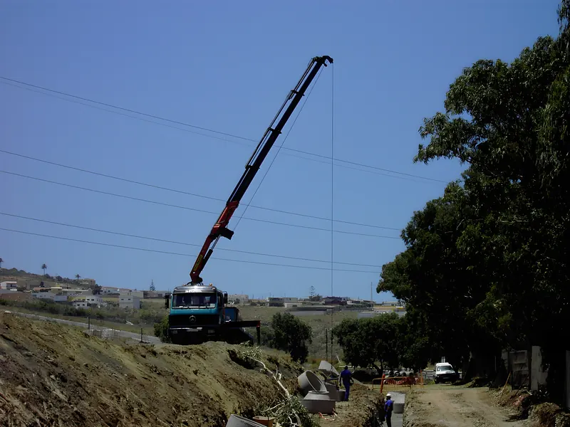 Camión grúa trabajando en una obra de canalización junto a una carretera