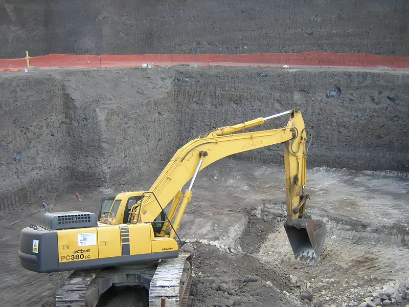 Excavadora de cadenas en el fondo de un vaciado con paredes de roca